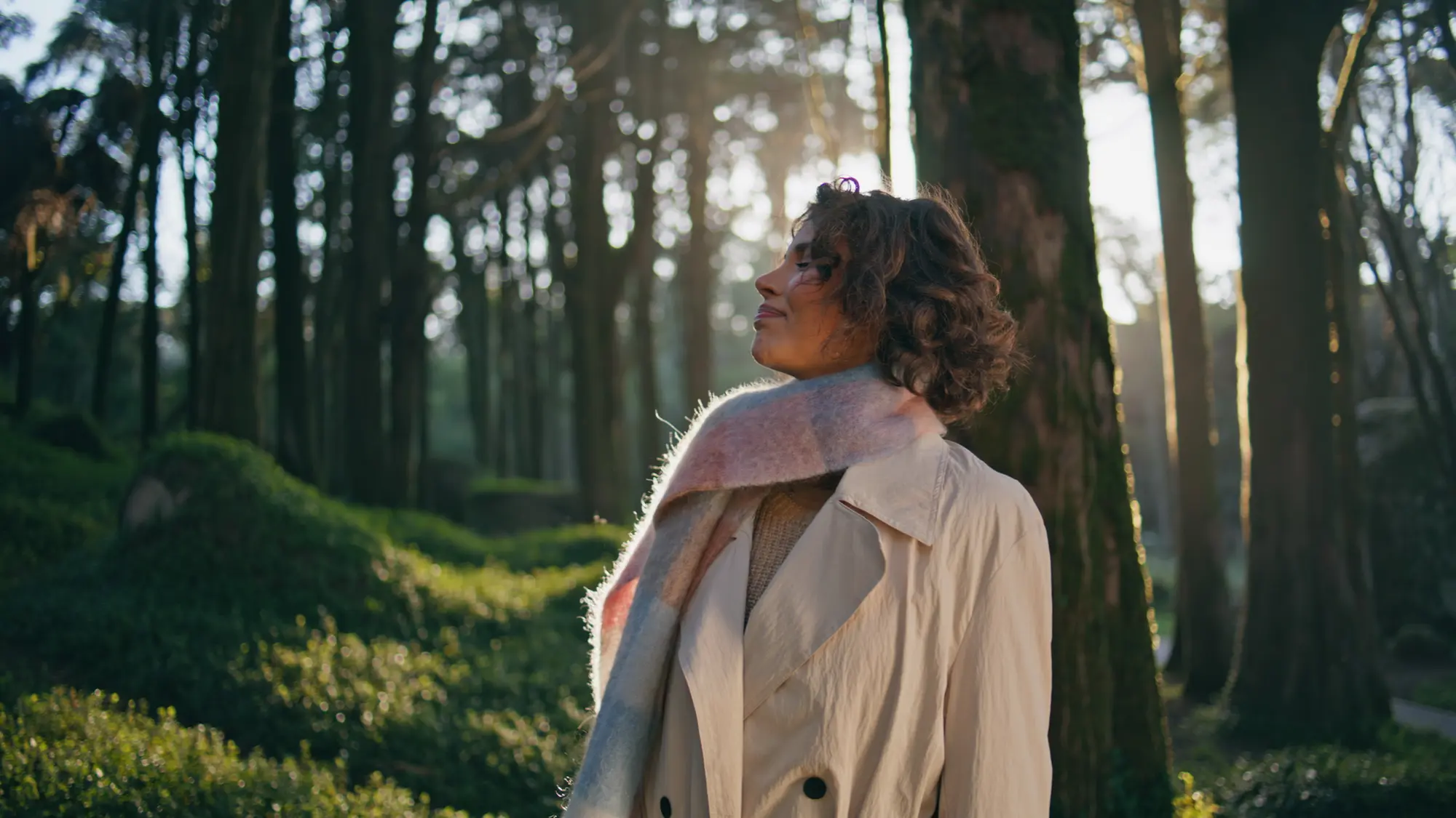 Mulher respira entre árvores iluminadas pelo fim da tarde